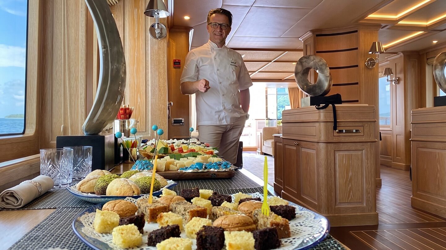 Hasan Emence behind a serving table with several food presentations.