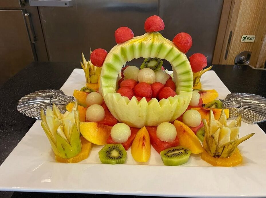 Assorted fruit pieces arranged around a carved fruit.