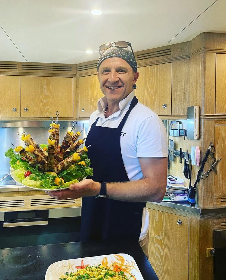 Hasan Emence holding a raised serving arrangement in a kitchen.