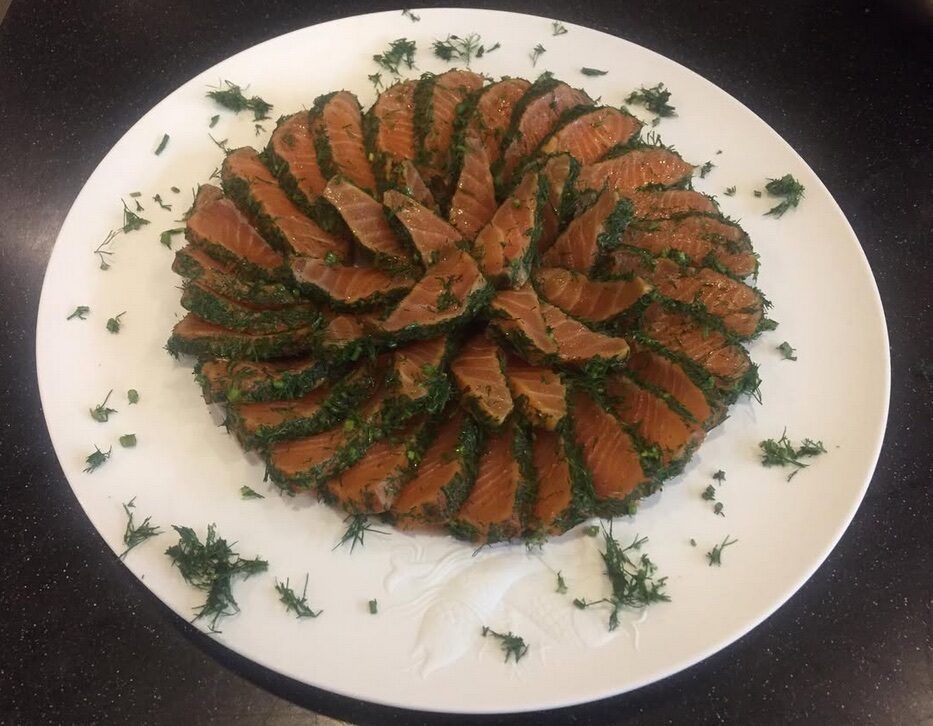Slices and greens arranged in a circle on a round white plate.