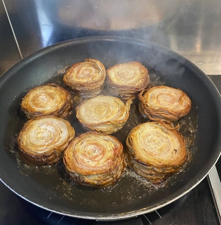 Round food preparations arranged side by side in a pan.