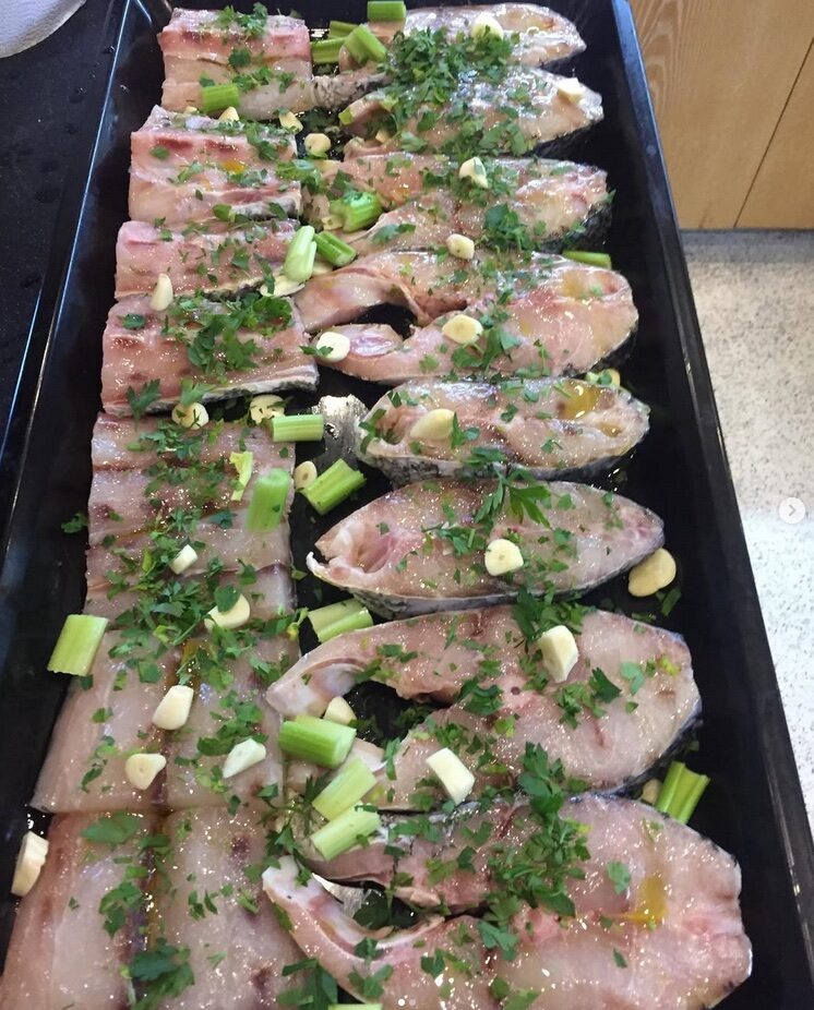 Portions arranged on a black tray and finished with greens.